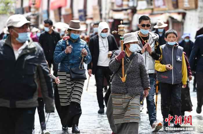 4月28日，信众手摇转经筒，顺着八廓街转经祈福。 何蓬磊 摄