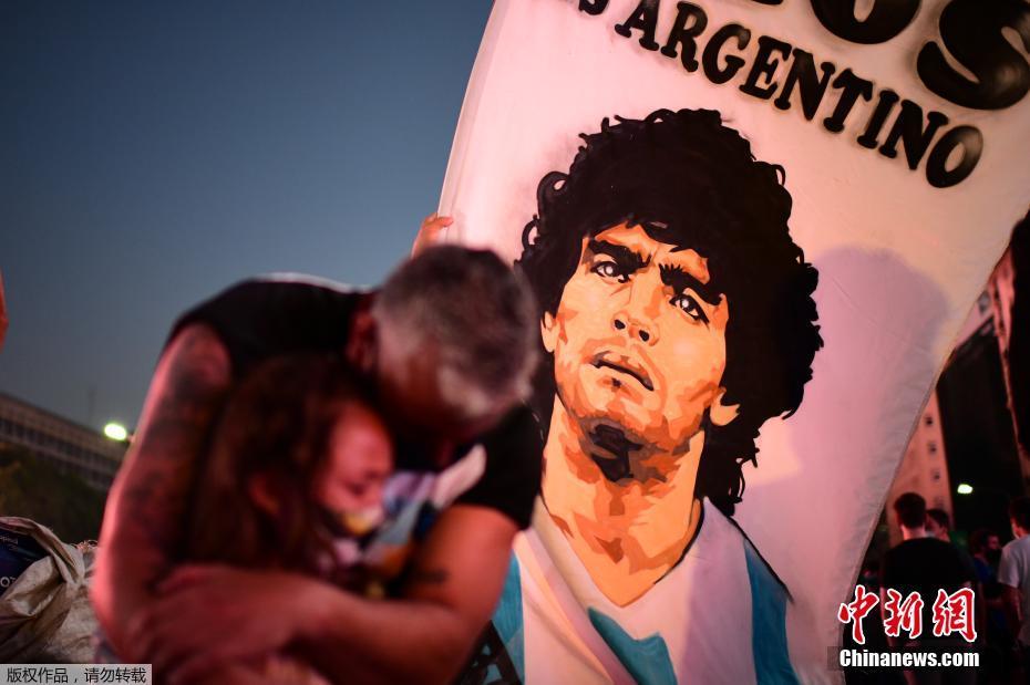 当地时间11月25日，阿根廷首都布宜诺斯艾利斯，一名男子搂着他的女儿悼念足球传奇人物迭戈·马拉多纳。这位带领阿根廷赢得1986年世界杯的足球巨星于当天突发心梗去世，享年60岁。